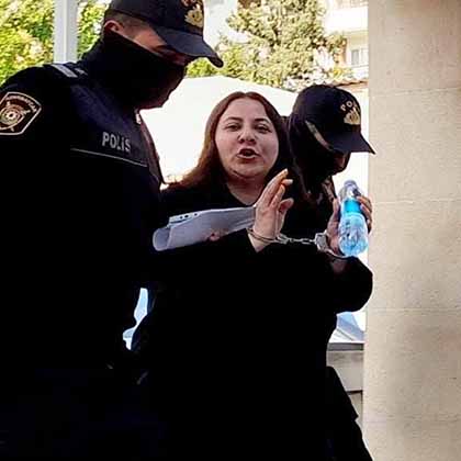 Ulviyya Guliyeva is taken away in handcuffs by two masked police officers.