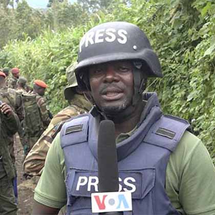 Photo of a VOA journalist wearing a helmet and flak jacket while reporting.