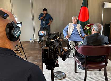 A VOA journalist holds a microphone to interview a woman on camera.