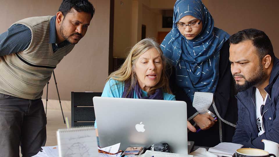 A VOA reporter leads a training session for three journalists, gathered around laptop computer in Cox’s Bazar, Bangladesh. (photo by Laurie Moy for USAGM)