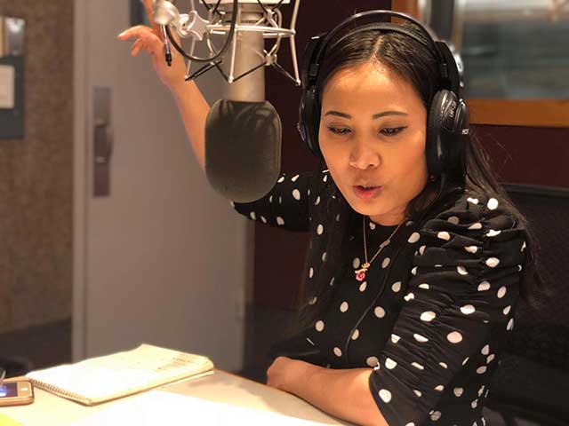 Photo of VOA journalist speaking into a radio microphone.