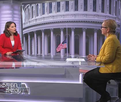 Two VOA reporters talking about U.S. elections at a table in a broadcast studio.