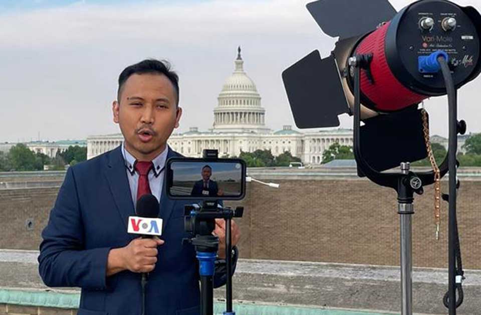 A VOA reporter broadcasts from the roof of the Cohen Building with the U.S. Capitol in the background.