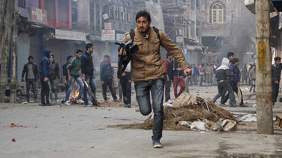 A VOA journalist runs down a street in Kashmir.
