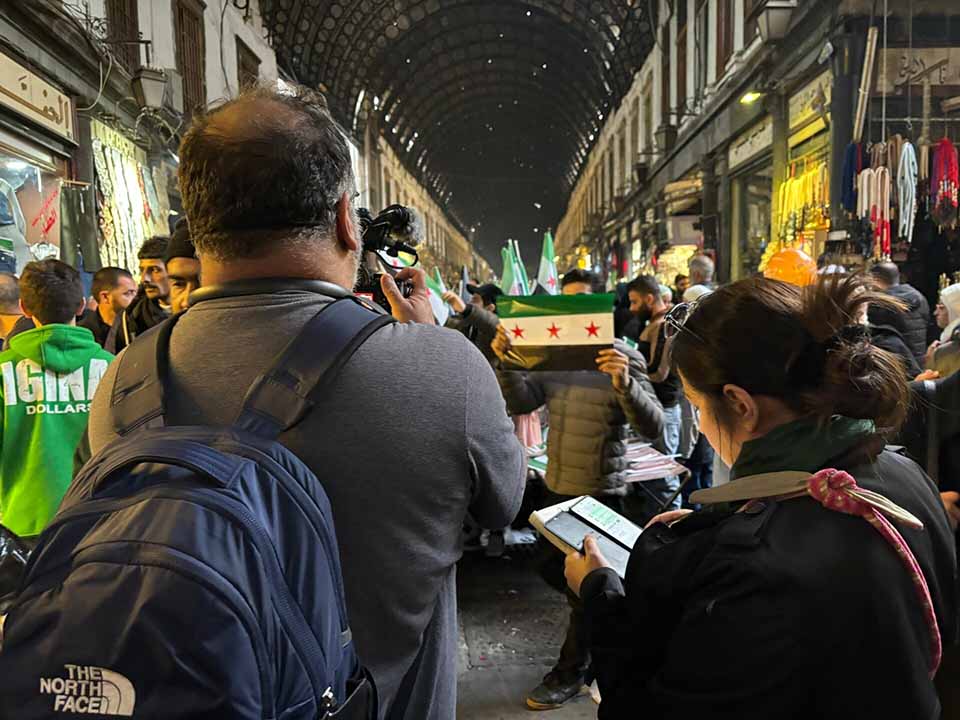 Two VOA journalists face a crowded market in Syria. 